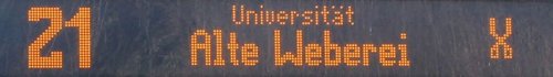 Eine elektronische Anzeigetafel zeigt die Nummer 21 sowie die Destination "Universität Alte Weberei" an.