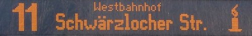 Eine digitale Anzeigenanzeige, die die Linie 11 zum Westbahnhof anzeigt, gefolgt von dem Ziel "Schwärzlocher Str." und einem Symbol einer kleinen Kerze.
